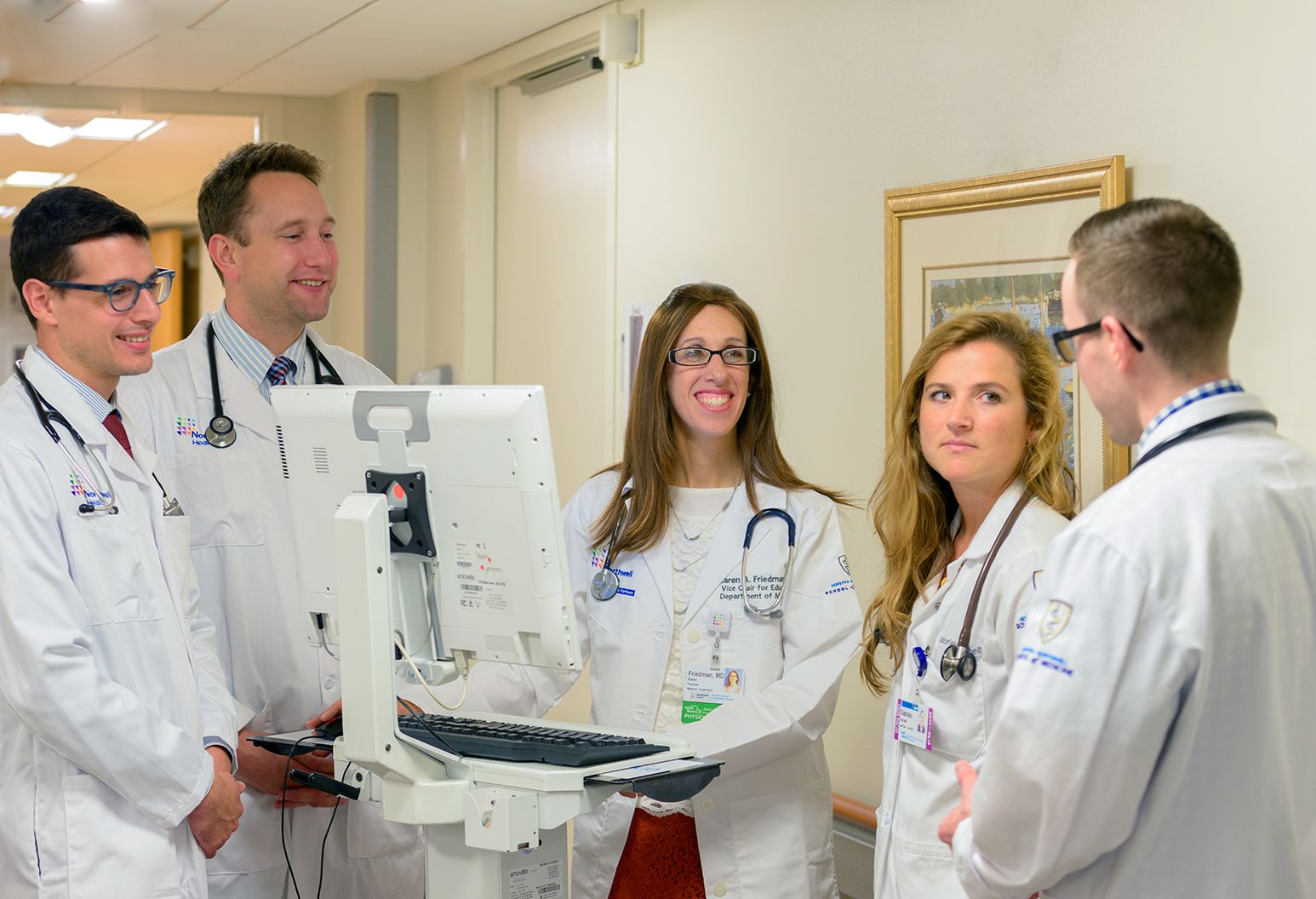 Five researchers with a mobile computer speaking in the hallway of the hospital.